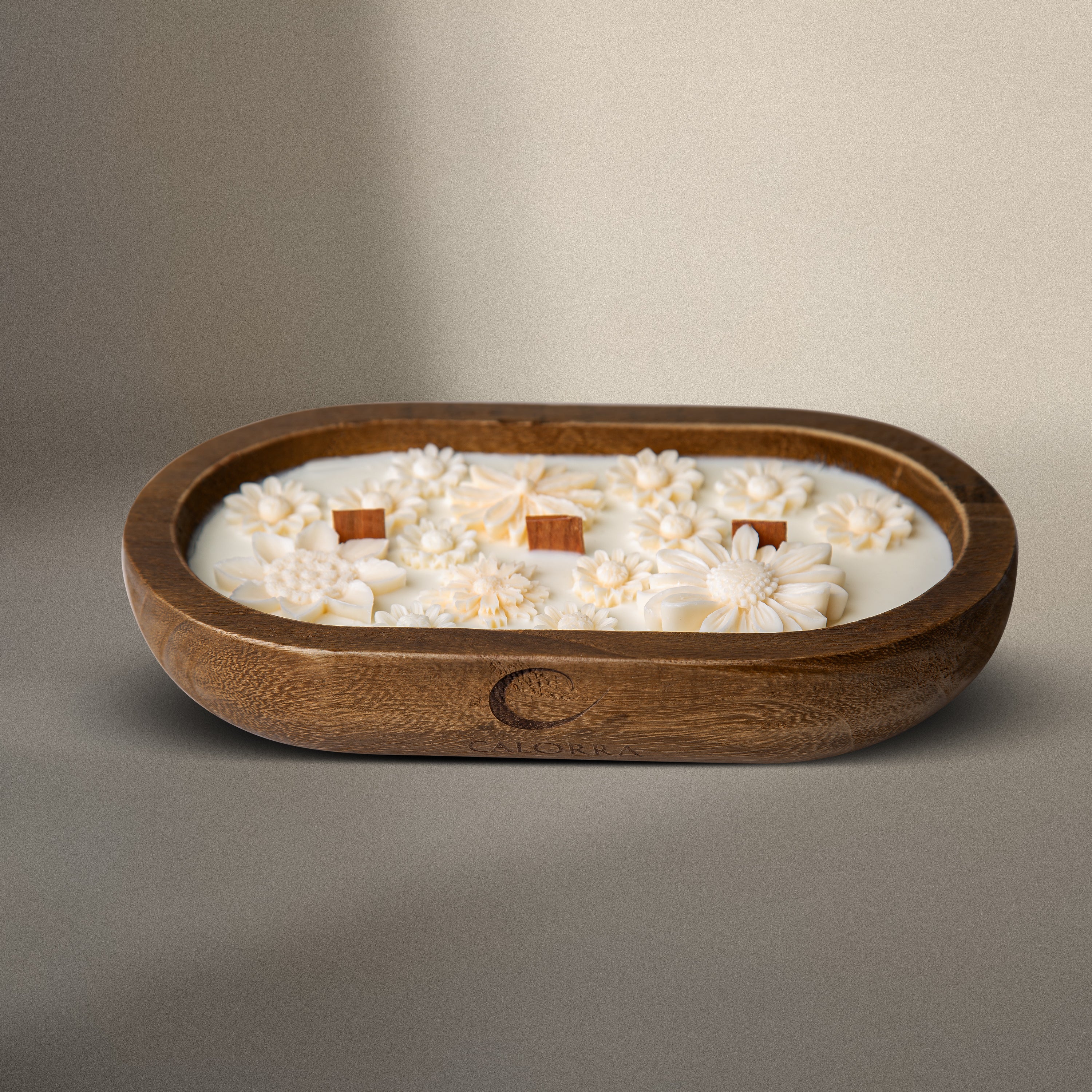 Luxury cedarwood scented candle Whispering Forest by Calorra in a handcrafted wooden jar with wax floral design and wooden wicks on a beige background